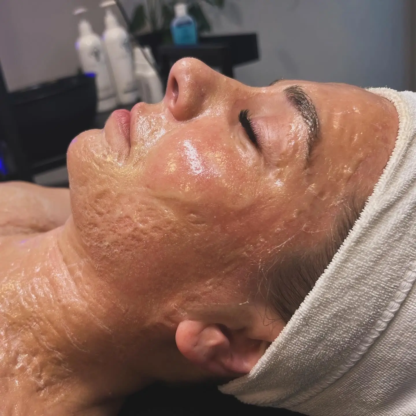 Kundin von Mission immerschön mit weißem Stirnband erhält eine Firming-Peptide Mask - Behandlung. Die Maske ist auf dem Gesicht aufgetragen